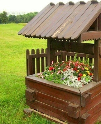 Des boîtes avec des fleurs sont placées sur la base, des plantes grimpantes sont plantées à côté.